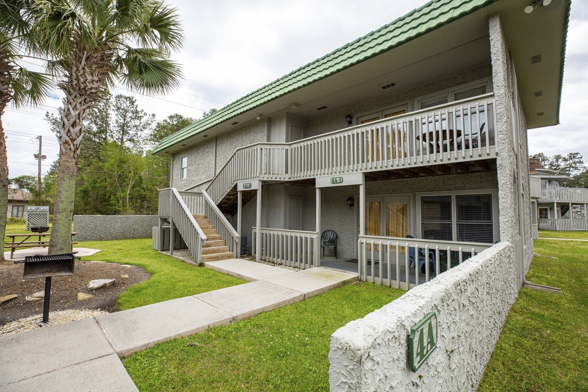 A two-story building with a balcony, a staircase, and a covered outdoor area.
