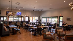 A spacious restaurant with multiple dining areas, large windows, and a bar counter. - 1BR Suite w/ Kitchen & Balcony Access (Branson)