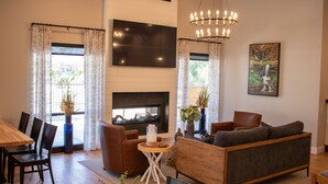 A modern living room with a fireplace, a large TV, and comfortable seating. - 1BR Suite w/ Kitchen & Balcony Access (Branson)