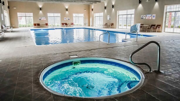 An indoor swimming pool with a diving board, lounge chairs, and a sunlit room with large windows. - 1BR Suite w/ Kitchen & Balcony Access (Branson)