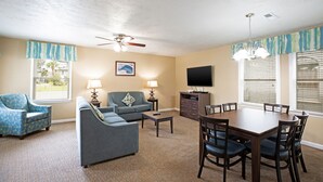 A living room with a sofa, armchair, coffee table, TV, and dining table with chairs. - Spacious 3BR Villa w/ Pool near Surfside Beach (Surfside Beach)