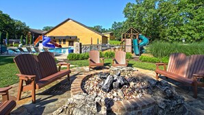 Una cabaña de madera con un hogar, asientos exteriores y una zona de piscina con toboganes.