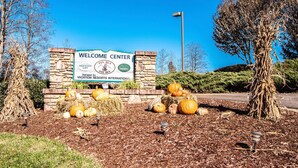 A welcome center with a signboard, surrounded by autumn pumpkins and trees.