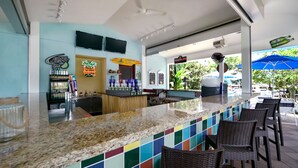 A bar area with a counter, bar stools, and a neon sign for Budweiser.