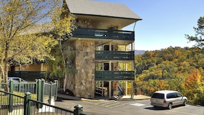 A two-story building with a stone facade, balconies, and a parking area.