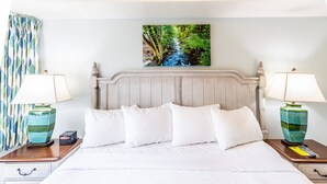 A neatly made bed with white linens, a wooden headboard, and two bedside tables with lamps.