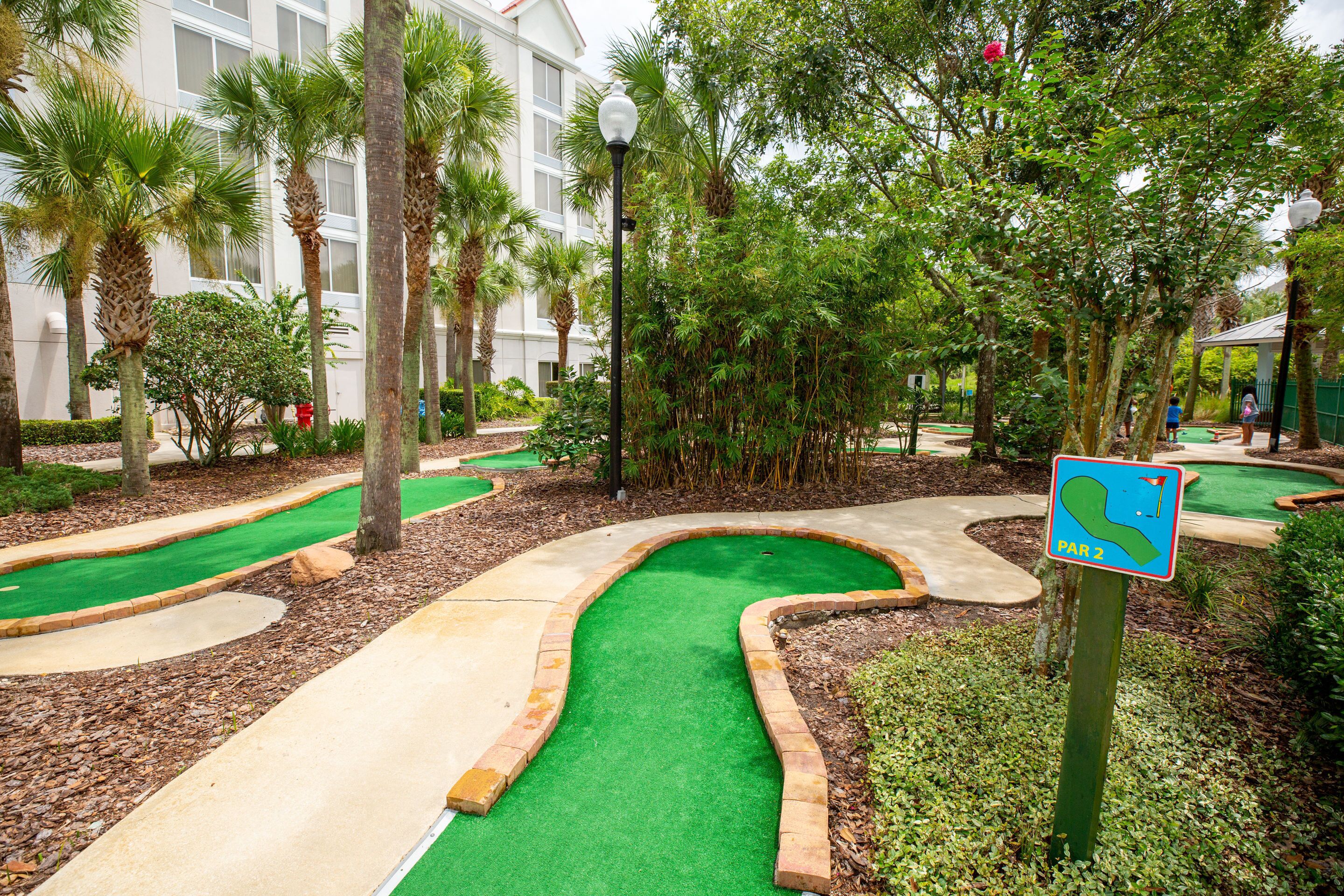 A miniature golf course with a green putting green, sand traps, and a sign indicating 'PAR 2'.