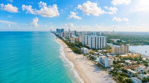 A coastal cityscape with high-rise buildings, a beach, and a marina.
