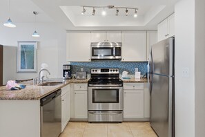 A modern kitchen with stainless steel appliances, a dishwasher, and a tiled backsplash.