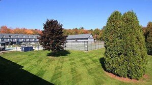 A building with a large glass facade, surrounded by well-maintained grass and a tall tree.