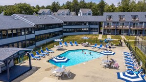 A pool area with lounge chairs and umbrellas, surrounded by buildings with large windows and balconies.