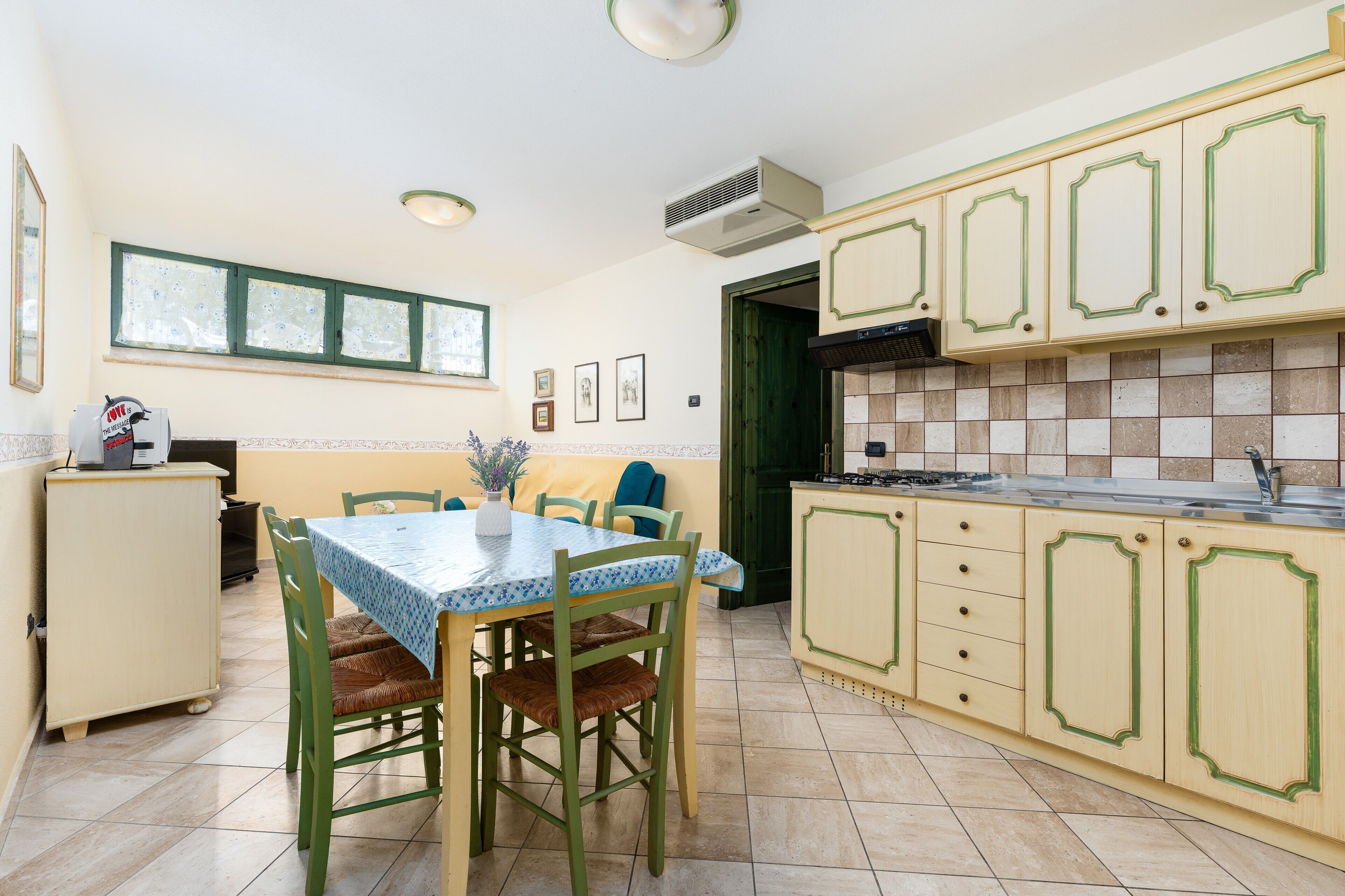 Una cucina con tavolo e sedie, pensili e una finestra.