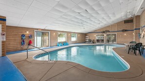 Una piscina interior con techo azulejado, paredes de madera y borde de piscina azul.
