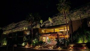 Un hôtel moderne doté d’une entrée imposante, de plusieurs étages et d’un jardin aménagé avec des palmiers.