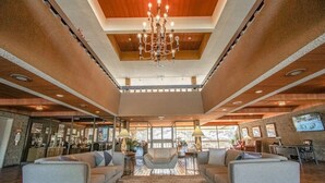Un vaste espace de vie agrémenté d’un grand lustre, de sièges confortables et offrant une vue sur l’extérieur.