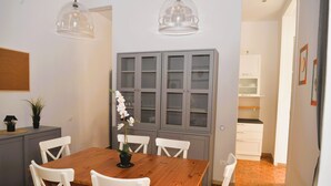 Ein Essbereich mit Holztisch, weißen Stühlen und einer Kommode mit Glastüren.