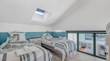A bedroom with two beds, a skylight, a view to the outside, and a small kitchenette.