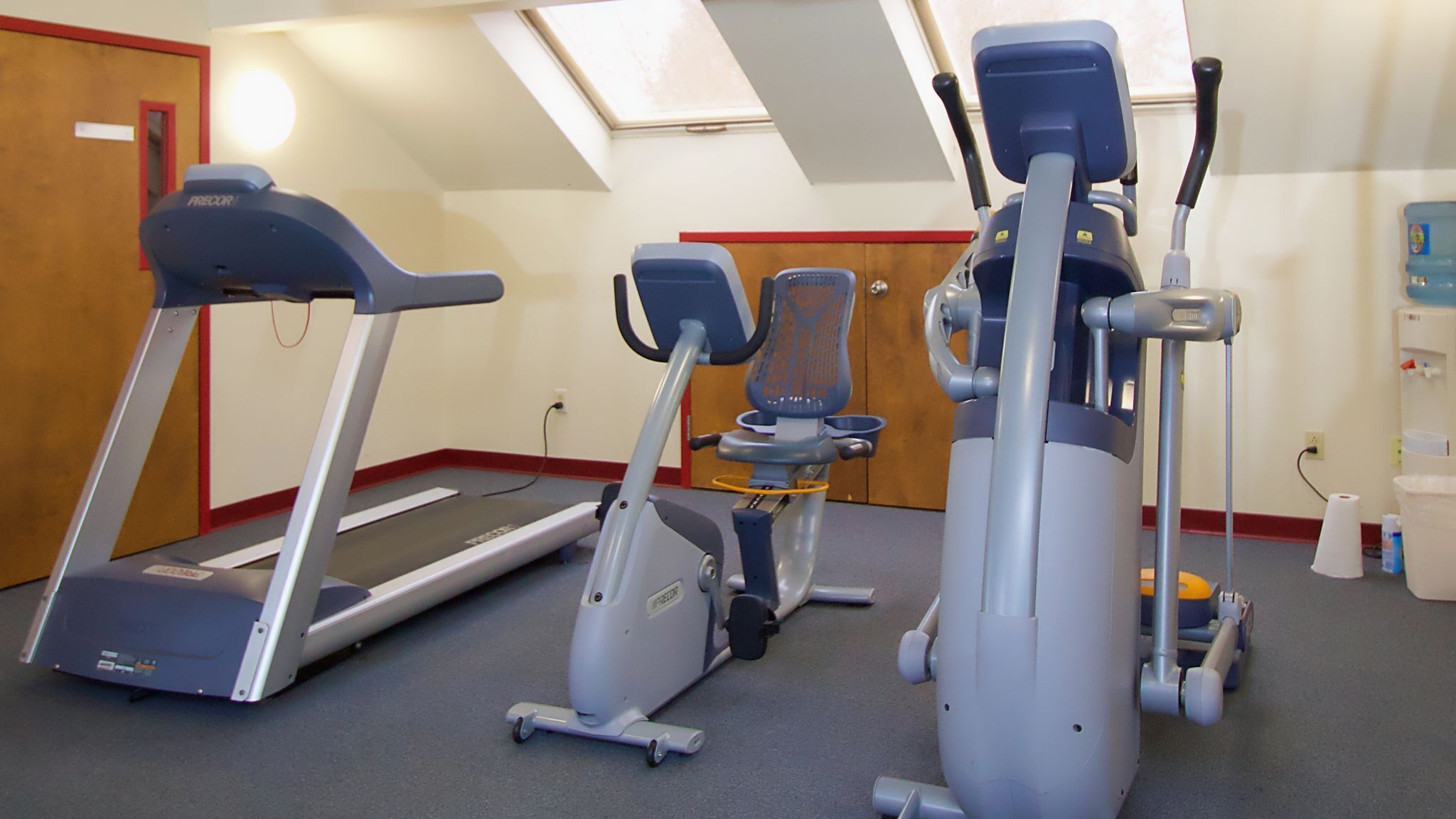 Une salle de sport équipée de tapis de course, d’un vélo elliptique et d’un vélo d’appartement.