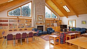 Un espacio habitable amplio con una gran mesa de madera, varias opciones de asiento y una chimenea.