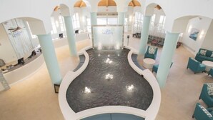 A spacious lobby with a central water feature, seating areas, and a reception desk.
