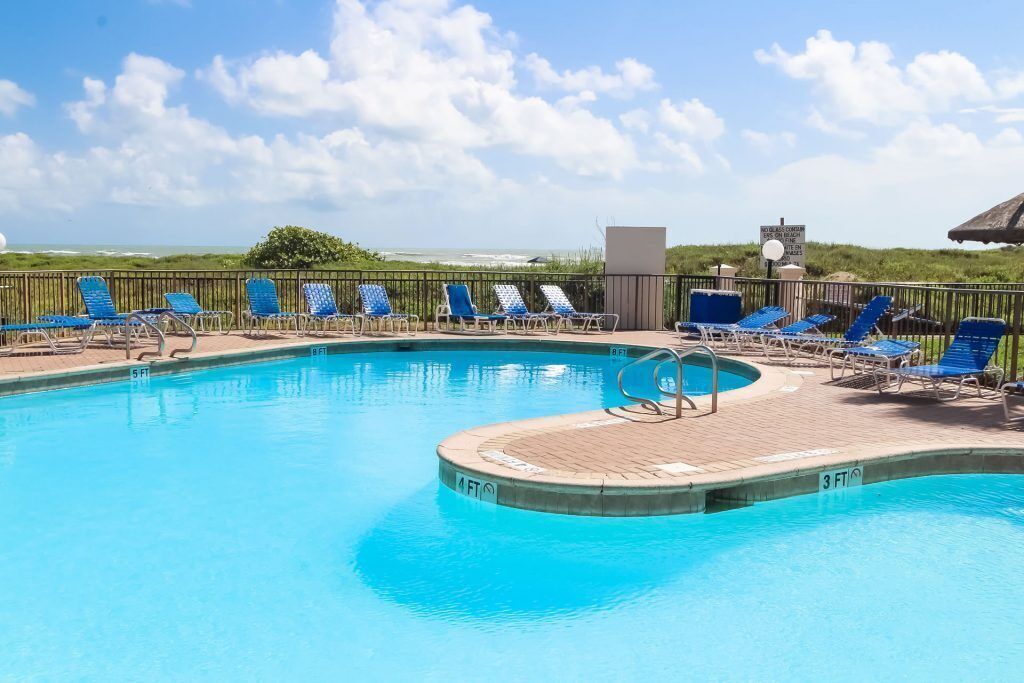 A swimming pool with lounge chairs and a lifeguard stand.