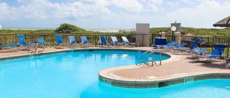 A swimming pool with lounge chairs and a lifeguard stand.