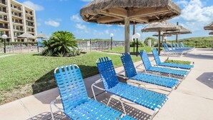 Een resort met buitenzitplaatsen, rieten parasols en een zwembad.