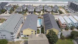 Zona residencial frente a la playa con edificios de varios pisos, una piscina visible y una playa al fondo.