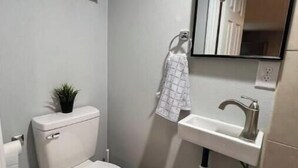 A compact bathroom with a toilet, sink, and mirror.