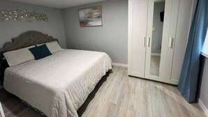 A bedroom with a bed, a wardrobe, and a painting on the wall.
