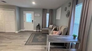 Un salón amplio con un sofá gris, una mesa de centro de madera y una alfombra.