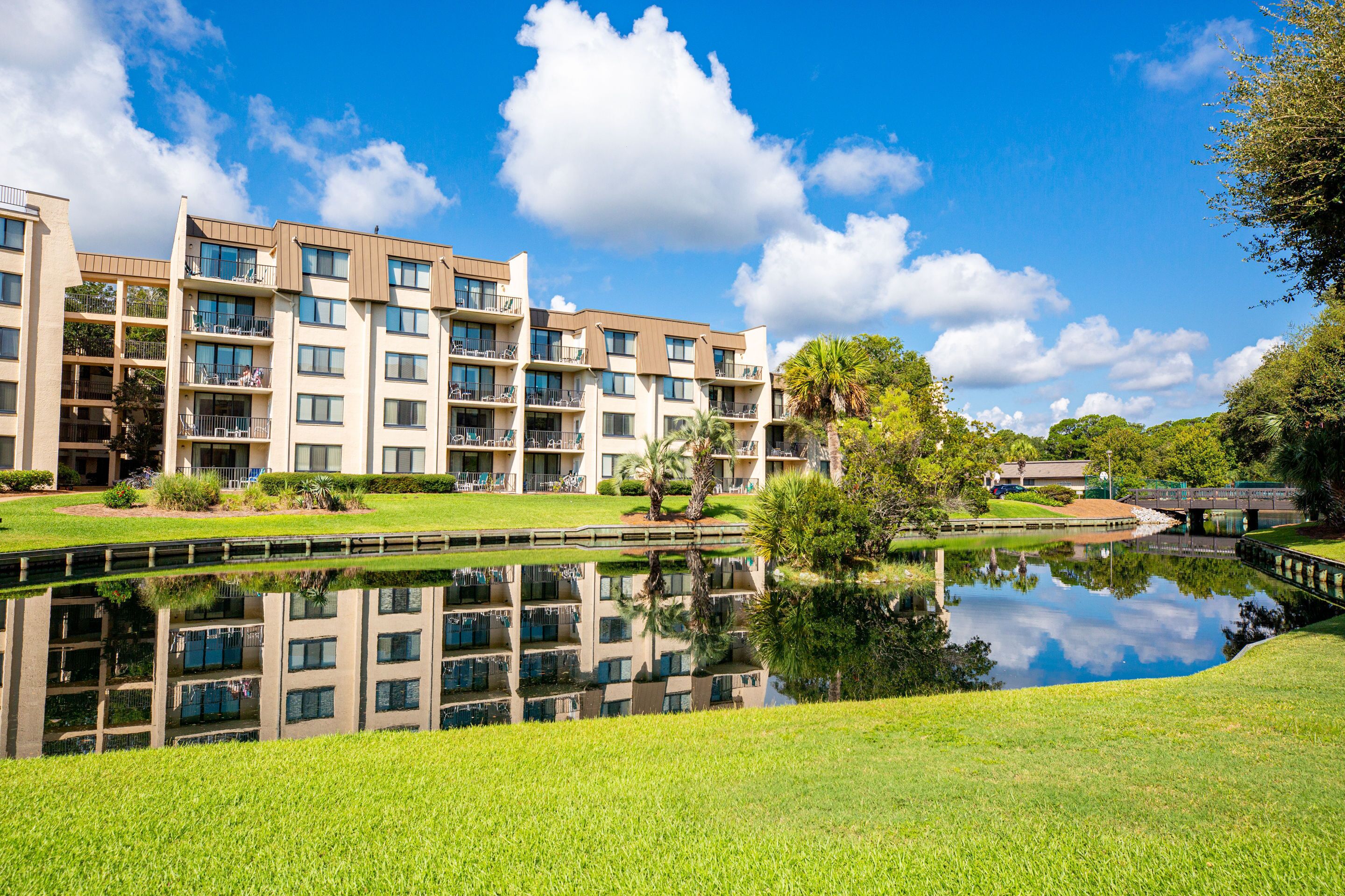 A multi-story hotel with balconies, a reflection pool, and a bridge.