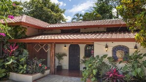 A two-story building with a tiled roof, a wooden door, and a mosaic wall. - A Tropical Paradise - Painted Pony Ranch B&B just 25 minutes to Pacific Beaches (Portegolpe)