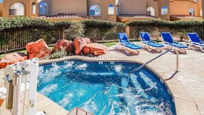 A swimming pool with blue tiles, surrounded by lounge chairs and large rocks. - Jacuzzi & Fireplace Retreat in Sedona (Sedona)