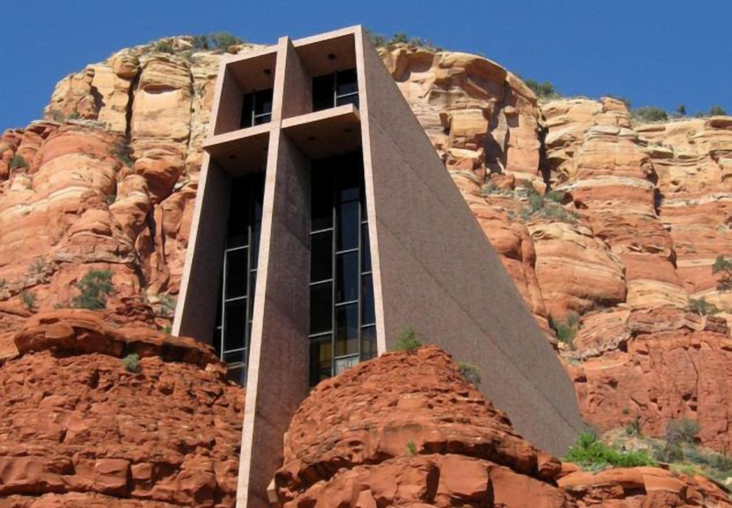 Un bâtiment doté d’une architecture originale, caractérisé par une structure imposante aux lignes angulaires, qui se détache sur un paysage de formations rocheuses rouges.