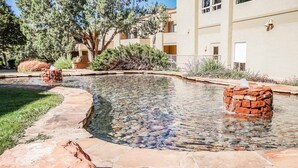 A clear pool with stone edges, surrounded by a stone pathway and landscaping. - Jacuzzi & Fireplace Retreat in Sedona (Sedona)