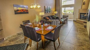 A dining area with a wooden table, black chairs, and a chandelier. There is a sofa and a television in the background. - Jacuzzi & Fireplace Retreat in Sedona (Sedona)
