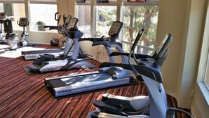 A gym with treadmills and exercise bikes, large windows, and a view of trees. - Jacuzzi & Fireplace Retreat in Sedona (Sedona)