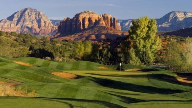 A golf course with rolling green hills, a flagstick, and a mountain range in the background. - Jacuzzi & Fireplace Retreat in Sedona (Sedona)