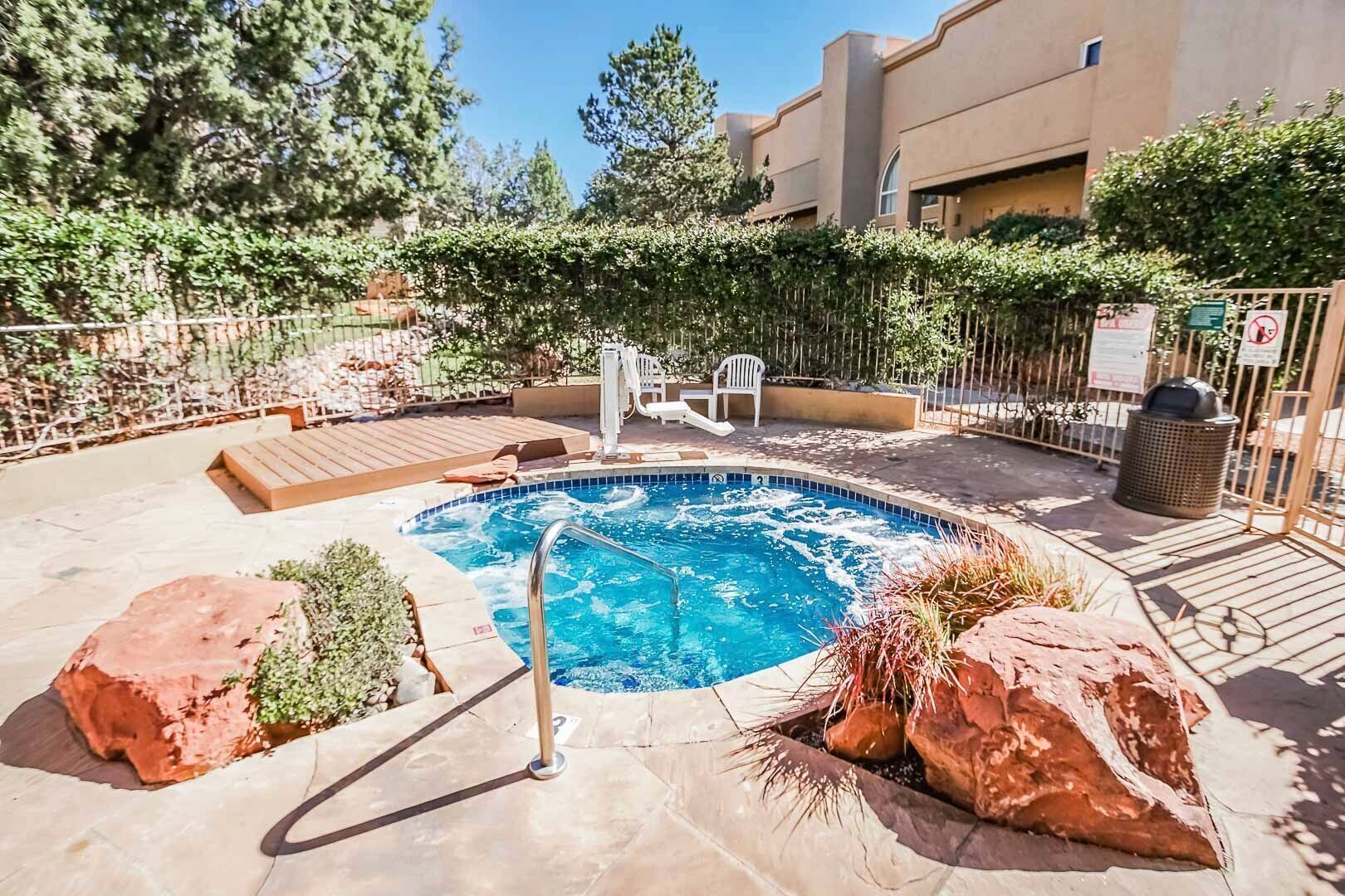 A hot tub surrounded by a wooden deck, with a metal railing and a trash can nearby.