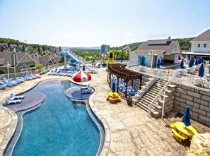 A water park with a swimming pool, lounge chairs, and a covered seating area.
