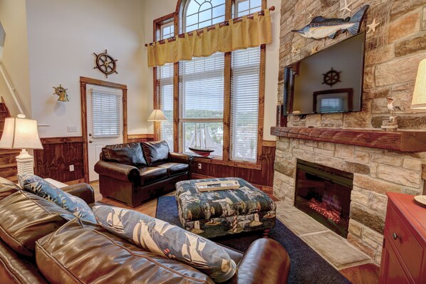 A cozy living room with leather sofas, a fireplace, and nautical decor. - 4-Bedroom Retreat near Silver Dollar City (Branson)