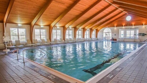 An indoor swimming pool with a wooden ceiling and arched windows. - 1-Bedroom Condo near Lake Wallenpaupack (Hawley)