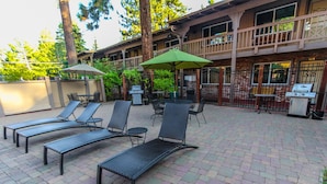 Un patio con sillones de descanso, una parrilla y un área de estar techada.