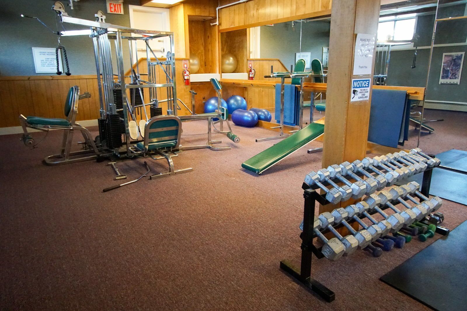 Une salle de sport équipée de machines d’exercice, d’un banc et d’haltères.