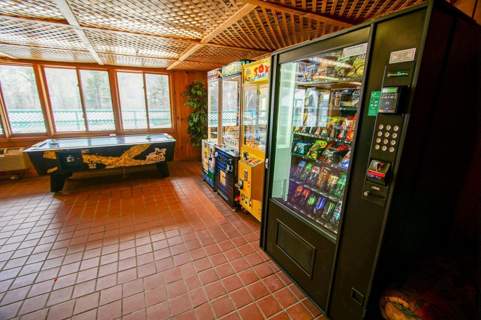 A room with a pool table, vending machines, and a large window.