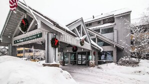 A hotel entrance with a sign reading "The Village of Loon Mountain." - Condo Nr Loon Mountain | King Bed + Balcony Views (Lincoln)