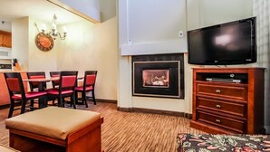 A living room with a fireplace, a television, a dining area with red chairs, and a patterned ottoman. - Spacious Loft Condo Near Loon Mountain (Lincoln)