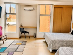 Ein Schlafzimmer mit einem Bett, einem Schreibtisch, einem Stuhl und einem Fenster.