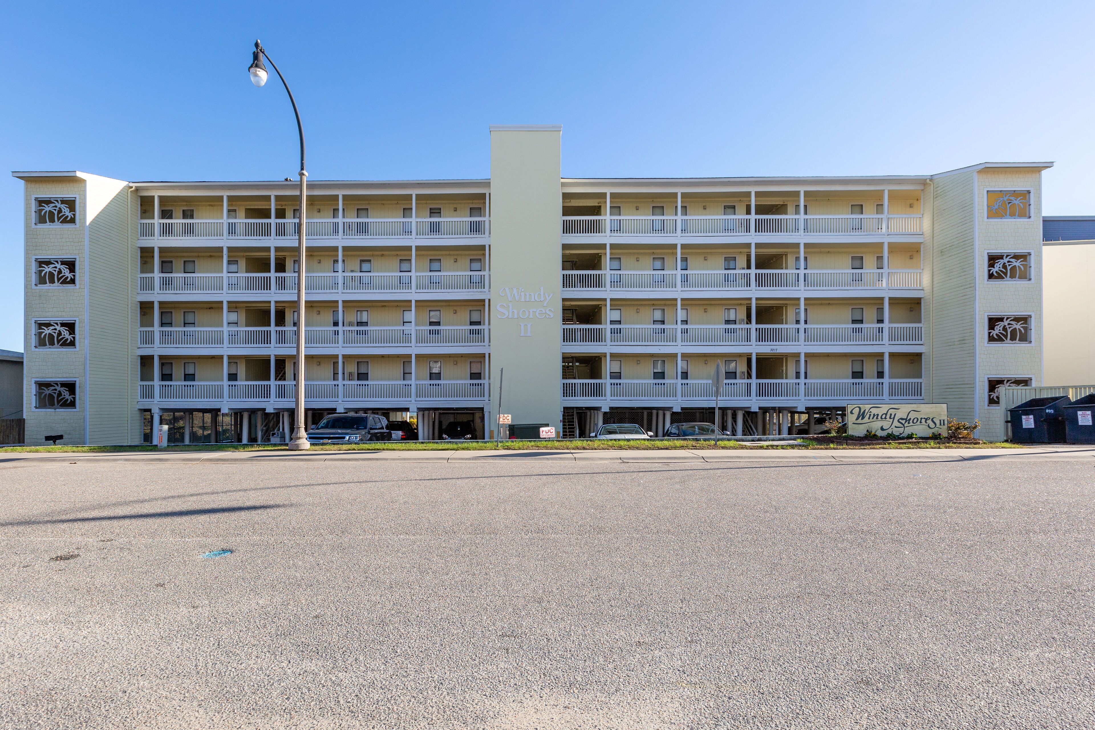 A multi-story motel with a central tower, balconies on each floor, and a parking lot in front.